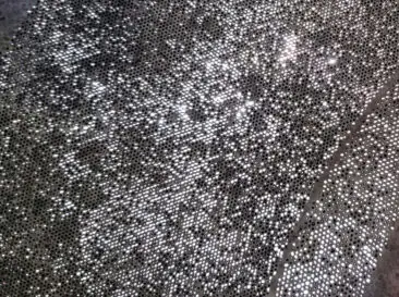 Close-up of stainless steel filter media after industrial cleaning, showing visible areas of remaining staining or embedded contamination.