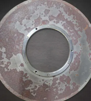 Stainless steel industrial filter with visible rust contamination before cleaning.