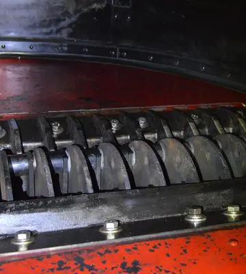 Close-up of cleaned grinder components and surrounding red-painted equipment after soot removal.