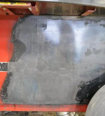 Cleaned exterior section of a red industrial hay grinder after soot and fire residue removal.
