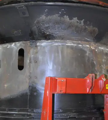 Exterior cylindrical section of an industrial hay grinder after fire residue and soot cleaning.