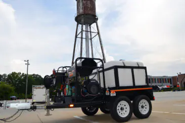 Trailer-mounted Merritt Industrial pressure washing equipment staged near an industrial water tower.